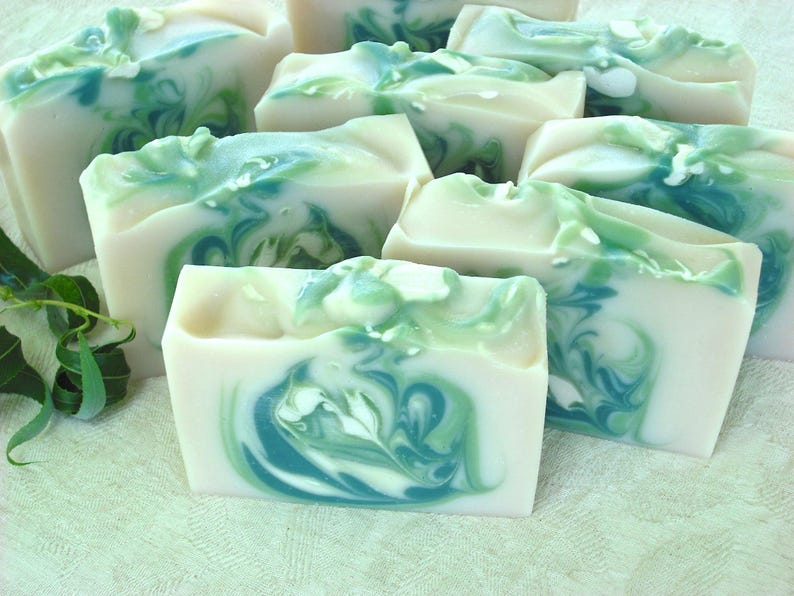 May include: A collection of handmade soap bars with a swirling green and white pattern. The soap bars are arranged on a white surface.