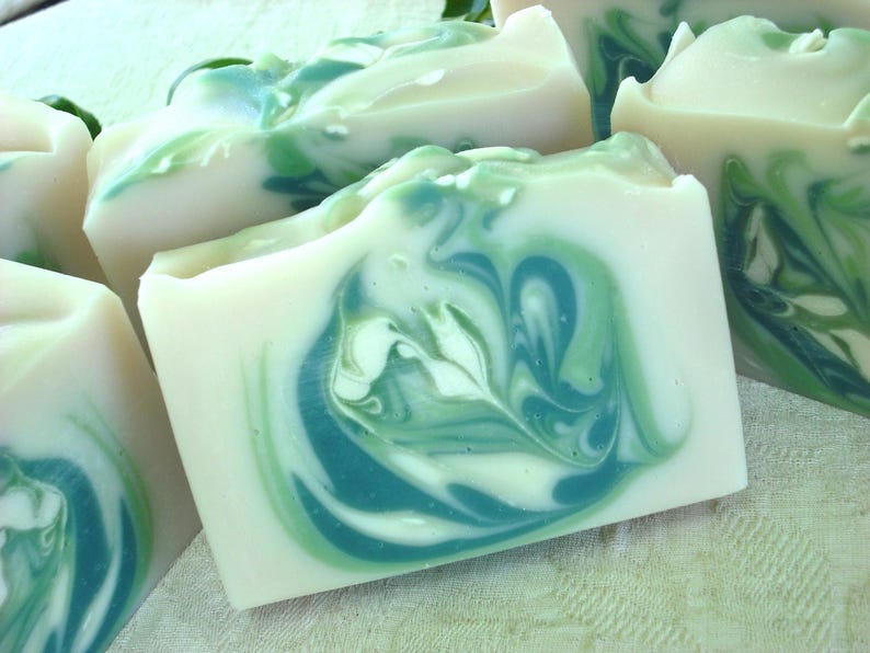 May include: Four bars of handmade soap with a swirling green and white pattern. The soap is made with natural ingredients and is perfect for sensitive skin.