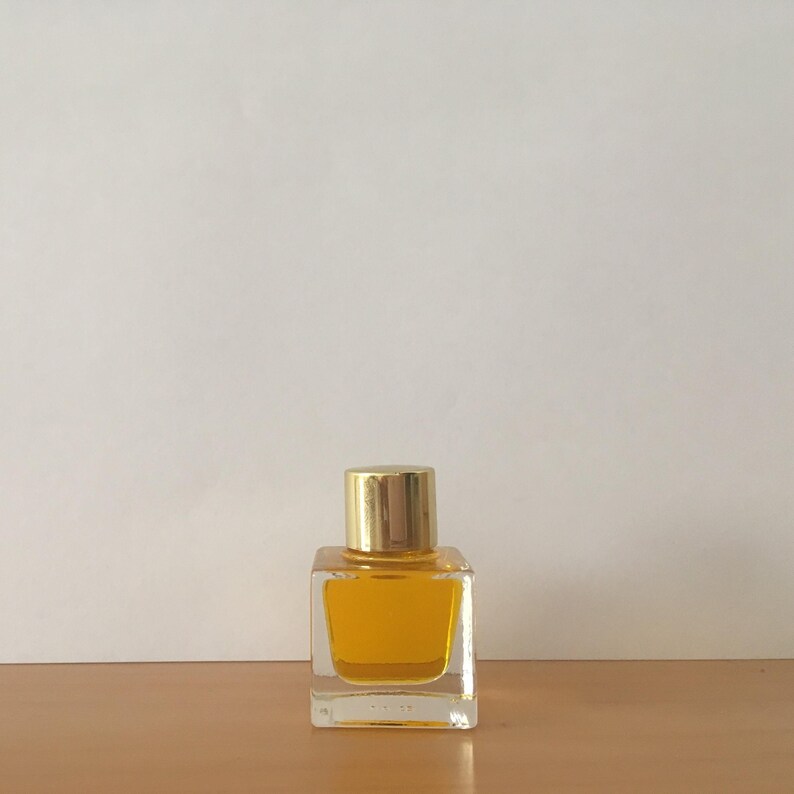A small, square perfume bottle with a gold cap. The bottle is filled with a yellow perfume. The bottle is sitting on a wooden surface, with a white background. Luxury Natural Perfume Gift Set: Floral Aromatherapy - Sovereign Collection