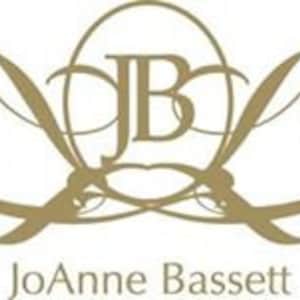 JoAnne Bassett Natural Perfumes gold-colored logo featuring the initials "JB" intertwined within an oval shape, with elegant, flowing lines and flourishes. The name "JoAnne Bassett" is written below in a serif font.