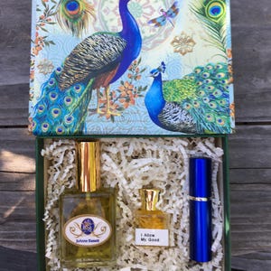 Luxury Natural Perfume Gift Set: Floral Aromatherapy - Sovereign Collection. A gift set featuring a box with peacock illustrations. Inside, a large perfume bottle with a gold cap, a smaller bottle with the text "I Allow My Good", and a blue atomizer