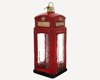 May include: Red glass Christmas ornament shaped like a traditional British telephone booth. The ornament has a gold top and the words "TELEPHONE" are printed on the sides.