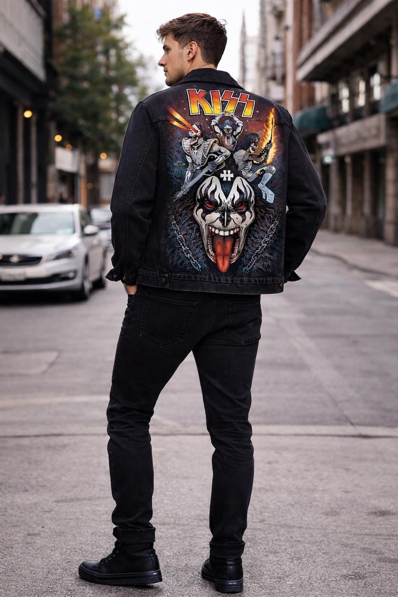 May include: Black denim jacket with a colorful graphic on the back featuring the band KISS. The graphic includes the band's logo and illustrations of the band members. The jacket is paired with black jeans and boots.