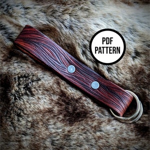 May include: A red leather strap with two silver rivets and a gold metal ring. The strap is on a brown furry surface. The text "PDF PATTERN" is in a white circle on the image.