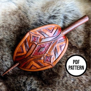 May include: A handcrafted leather hair stick with an oval, leaf-like design. The hair accessory features geometric patterns and red accents. The wooden pin is inserted through the leather piece. The image includes a white circle with the text "PDF PATTERN".