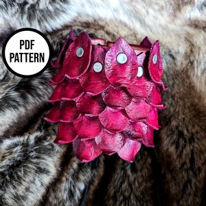 Könnte beinhalten: Eine rote Lederkette mit einem Schuppenmuster und silbernen Nieten. PDF PATTERN steht auf einem schwarzen Kreis.