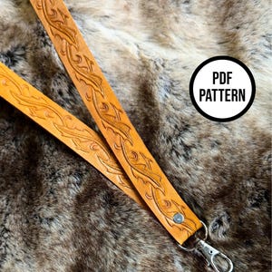 May include: A brown leather lanyard with a decorative floral pattern and a silver swivel clasp. The lanyard is on a faux fur background. The text "PDF PATTERN" is in a white circle on the image.