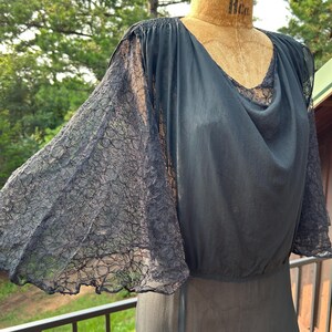 Peut inclure: Un chemisier noir dot&eacute; de manches &eacute;vas&eacute;es en dentelle transparente et d'un d&eacute;collet&eacute; drap&eacute;. Le v&ecirc;tement pr&eacute;sente des &eacute;paules fronc&eacute;es et une taille ajust&eacute;e, confectionn&eacute; dans un tissu l&eacute;ger et semi-transparent cr&eacute;ant une silhouette fluide.