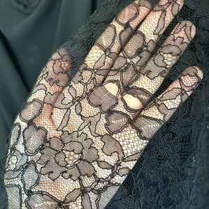 Peut inclure: Un tissu en dentelle noire transparente pr&eacute;sentant un motif floral d&eacute;taill&eacute; avec des bords festonn&eacute;s complexes et un fond en maille fine. Le textile d&eacute;licat affiche un motif botanique r&eacute;p&eacute;titif avec des p&eacute;tales et des feuilles en fil noir.