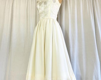 Peut inclure: Robe vintage ivoire avec un corsage ajusté et une jupe ample. Le corsage présente des détails de dentelle florale délicate. La robe est présentée sur un mannequin vintage sur fond neutre. Design classique et élégant.