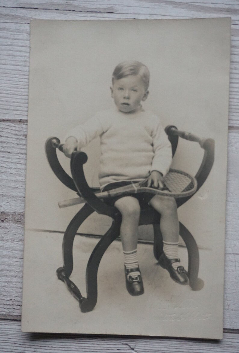 Rppc Of A Young Boy Sitting In A Chair Holding A Tennis Racket Wearing Jumper Shorts Socks And Shoes Social History