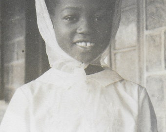 photographie vintage, jeune femme africaine en robe blanche, foulard, grand sourire, copie brute