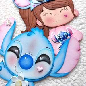 May include: A whimsical, layered craft featuring the character Stitch from Lilo & Stitch. The blue and pink Stitch figure holds a white flower. A girl wearing a Stitch-themed headband and a pink shirt is also depicted. The craft has a 3D effect.
