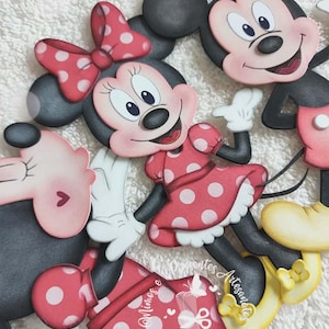 May include: A collection of Minnie and Mickey Mouse cutouts. Minnie Mouse is wearing a red dress with white polka dots and a matching bow. Mickey Mouse is smiling with his iconic black ears. The cutouts are likely for crafting or decoration.