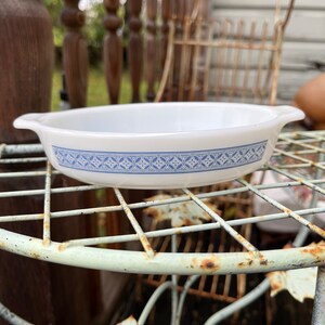 May include: White oval baking dish with a blue and white patterned border. The dish has two handles on the sides.