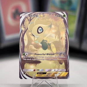 May include: A Pokemon trading card featuring Celebi EX, a light green and yellow mythical Pokemon with large eyes. The card has a gold background with a purple border and the text "Celebi EX" and "Powerful Bloom" in black. The card has a HP of 130 and a retreat cost of one colorless energy.