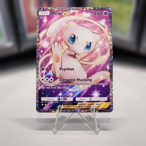 May include: A pink and purple Pokemon card featuring Mew EX with a gold border. The card has a picture of Mew EX with a pink background and stars. The card has the text "Mew EX" and "HP 130" in the top right corner. The card has the text "Psyshot" and "Genome Hacking" in the bottom left corner. The card has the text "20" and "+20" in the bottom right corner.
