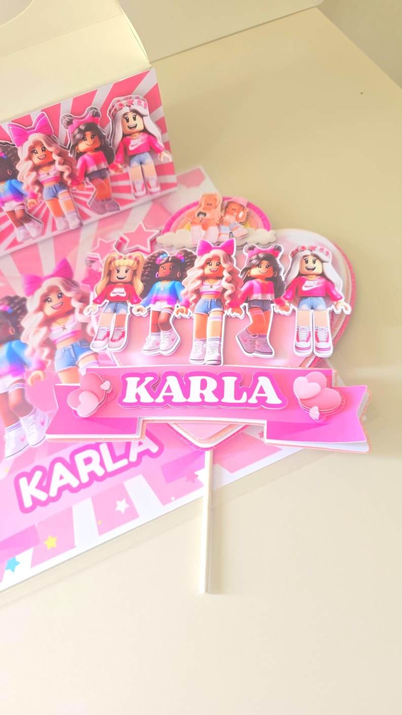 May include: A pink and white cake topper with the name "KARLA" in large, bold letters. The topper features several doll figures wearing pink tops and denim shorts. The overall design is bright and cheerful, perfect for a birthday celebration.