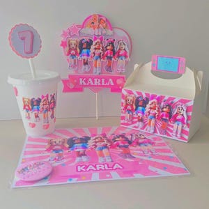 May include: A party set featuring a pink and white theme with cartoon character illustrations. Includes a cup, cake topper, gift box, placemat, and a pin. The name "KARLA" is printed on the placemat and cake topper.
