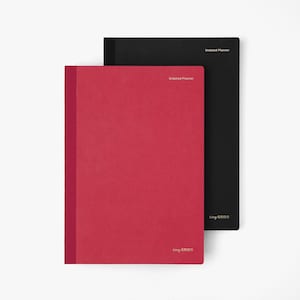 May include: Two undated planners, one red and one black, are stacked against each other. The red planner is in the foreground, with the black planner slightly behind it. The words "Undated Planner" and "tiny GRIDS" are printed on the covers.