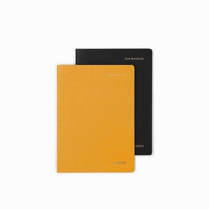 May include: Two notebooks, one mustard yellow and one black, are stacked on a white background. The yellow notebook has the word "GRIDS" printed at the bottom. The black notebook has the words "Grid Notebook" printed at the top.