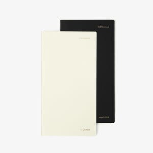 May include: Two rectangular notebooks, one cream-colored and one black, are stacked. The cream notebook has the text "Grid Notebook" and "tiny GRIDS" printed in a light color. The black notebook has the text "Grid Notebook" and "tiny GRIDS" printed in gold.