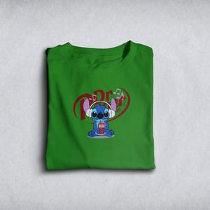 Może przedstawiać: Zielona koszulka z postacią z kresk&oacute;wki w słuchawkach i trzymającą nap&oacute;j. Projekt zawiera nuty muzyczne i napis "Dr". Postać jest niebieska z dużymi uszami.