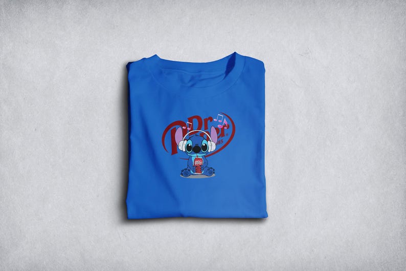 Może przedstawiać: Złożona kr&oacute;lewska niebieska koszulka z postacią z kresk&oacute;wki w słuchawkach i trzymającą nap&oacute;j. Grafika zawiera tekst "Dr. Pepper" w kształcie serca z nutami.