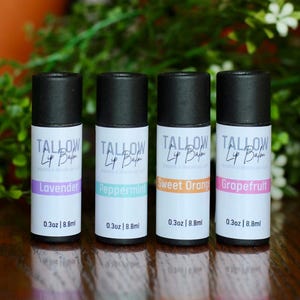 May include: Four lip balm tubes with black lids and white labels. Each label has the word "TALLOW" and the flavour: Lavender, Peppermint, Sweet Orange, and Grapefruit. Each tube is 0.3oz | 8.8ml.
