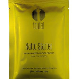 Op de afbeelding: Een gele verpakking met Natto Starter cultuurpoeder. De verpakking heeft de merknaam "trufal" en de tekst "Natto Starter" in een gestileerd lettertype. De tekst "NATTO STARTER CULTURE POWDER (PACK OF 6 SACHETS)" en "TRADITIONAL NATTO STARTER POWDER (For culinary use)" zijn ook zichtbaar.