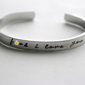 May include: A silver bracelet with the inscription "f**k i love you" engraved on it.