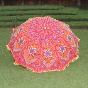 May include: A large, red, pink, and yellow patterned umbrella with gold fringe. The umbrella is decorated with embroidered flowers and stars.