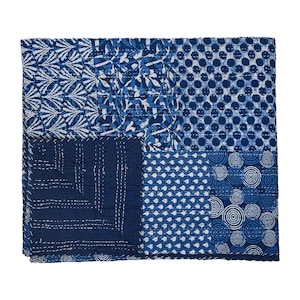 Peut inclure: Une courtepointe carrée en patchwork dans les tons de bleu et de blanc. La courtepointe est divisée en plusieurs sections, chacune avec un motif différent, notamment des pois, des motifs floraux et des formes géométriques. La courtepointe est en tissu et présente des coutures visibles.