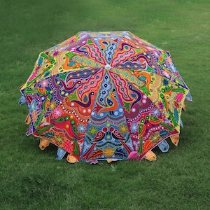 Pode incluir: Um guarda-chuva colorido, costurado &agrave; m&atilde;o, com um design vibrante de flores e p&aacute;ssaros. O guarda-chuva &eacute; feito de tecido e tem uma pega de madeira.