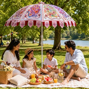 May include: A large, decorative outdoor umbrella featuring intricate, colorful embroidered peacock patterns on a white fabric canopy, finished with a scalloped red and pink fabric trim edge, supported by a central white metal pole.