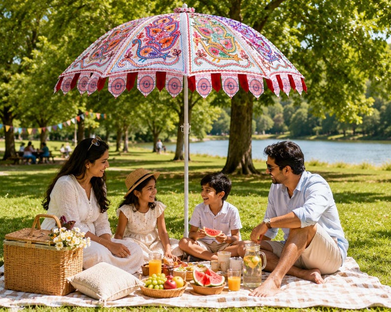 May include: A large, decorative outdoor umbrella featuring intricate, colorful embroidered peacock patterns on a white fabric canopy, finished with a scalloped red and pink fabric trim edge, supported by a central white metal pole.
