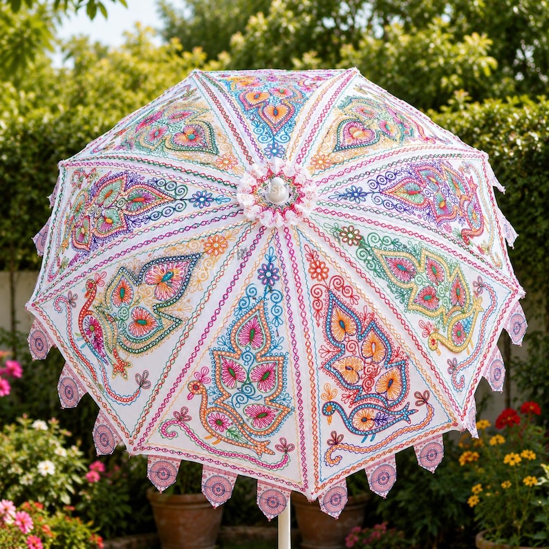 May include: A white parasol featuring intricate, multi-colored embroidery of stylized birds and floral patterns across its panels. The edges are finished with small, circular, embroidered scalloped accents and a central white finial top.