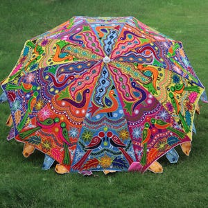 Pode incluir: Um guarda-chuva colorido, costurado &agrave; m&atilde;o, com um design vibrante de flores e p&aacute;ssaros. O guarda-chuva &eacute; feito de tecido e tem uma pega de madeira.