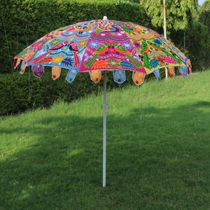 Pode incluir: Um guarda-chuva colorido e estampado com um poste branco. O guarda-chuva tem uma borda de franja e apresenta p&aacute;ssaros e desenhos florais bordados.