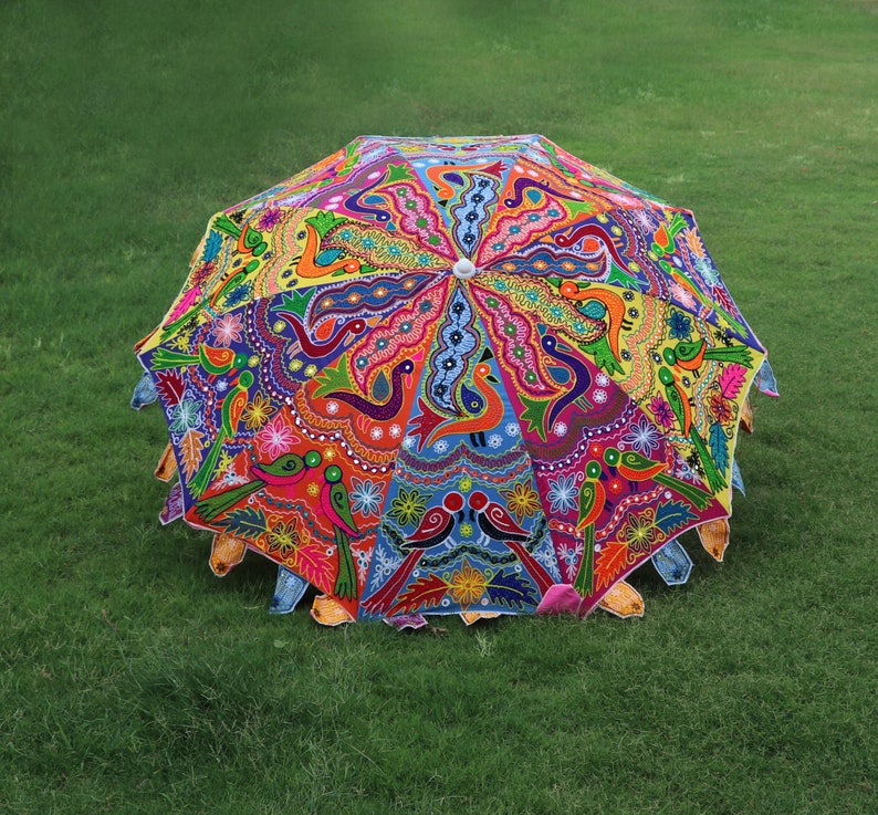 Pode incluir: Um guarda-chuva colorido, costurado &agrave; m&atilde;o, com um design vibrante de flores e p&aacute;ssaros. O guarda-chuva &eacute; feito de tecido e tem uma pega de madeira.