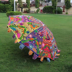 Pode incluir: Um guarda-chuva colorido, costurado &agrave; m&atilde;o, com um design floral e de p&aacute;ssaros. O guarda-chuva &eacute; feito de tecido e tem uma pega de madeira.