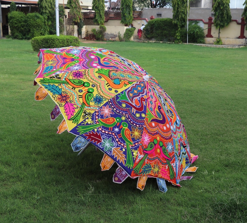Pode incluir: Um guarda-chuva colorido, costurado &agrave; m&atilde;o, com um design floral e de p&aacute;ssaros. O guarda-chuva &eacute; feito de tecido e tem uma pega de madeira.