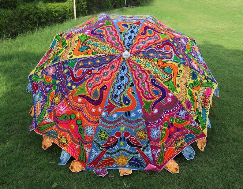 Pode incluir: Um guarda-chuva colorido pintado &agrave; m&atilde;o com um design vibrante de flores e p&aacute;ssaros. O guarda-chuva &eacute; feito de tecido e tem uma pega de madeira.