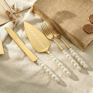 May include: A gold-toned cake knife, a cake server, and two forks with white pearl-like bead handles. The knife is engraved with "Lennox & Lexi" and a date, the server with "Till death do us part", and the forks with the word "Me too".