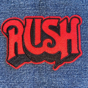 May include: Red and black embroidered patch with the word "RUSH" in a stylized font.
