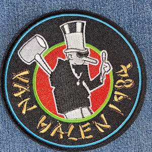 May include: Embroidered patch featuring a cartoon figure in a top hat and sunglasses, holding a hammer and giving a thumbs-up. The patch has a black background with a red and green inner circle, and the text "VAN HALEN 1984" in gold.