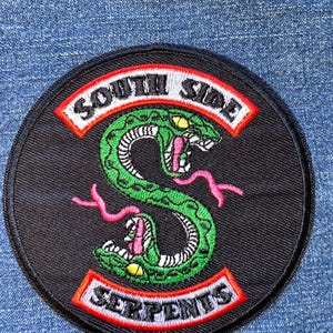 May include: A round black patch with the words "SOUTH SIDE SERPENTS" in white lettering, outlined in red. A green snake with pink tongue and yellow eyes is in the center.