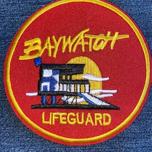 May include: A red and yellow embroidered patch with the words "BAYWATCH LIFEGUARD" and a cartoon image of a lifeguard stand with a blue and white striped flag.