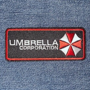 May include: A black and red embroidered patch with the text "UMBRELLA CORPORATION" and a white and red umbrella logo.