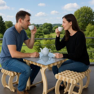 Op de afbeelding: Een stel drinkt thee aan een kleine tafel met bijpassende krukjes. De tafel heeft een glazen blad en een unieke houten basis. Op de tafel staan een witte theepot en kopjes, met een schilderachtige buitenachtergrond.